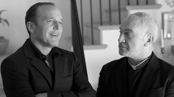 Movie still from “Much Ado About Nothing” (2012), directed by Joss Whedon – A couple of men sitting next to each other; Close Up shot, Over the shoulder angle