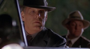 Movie still from “Mulholland Falls” (1996), directed by Lee Tamahori – A person wearing a suit and a hat; Close Up shot, Low angle