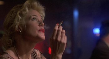 Movie still from “Mulholland Falls” (1996), directed by Lee Tamahori – A woman is holding a cigarette in her hand; Close Up shot, Low angle