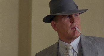 Movie still from “Mulholland Falls” (1996), directed by Lee Tamahori – A man in a suit and a hat smoking a cigarette; Close Up shot, Low angle