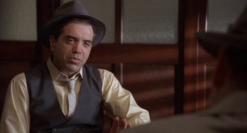 Movie still from “Mulholland Falls” (1996), directed by Lee Tamahori – A man wearing a hat sitting in front of a table; Close Up shot, Over the shoulder angle