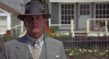 Movie still from “Mulholland Falls” (1996), directed by Lee Tamahori – A man in a suit and hat standing in front of a house; Close Up shot, Low angle