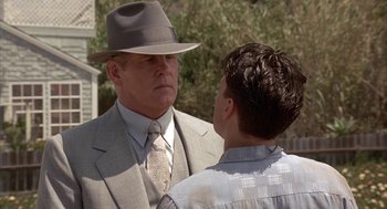 Movie still from “Mulholland Falls” (1996), directed by Lee Tamahori – A man wearing a suit and hat talking to another man wearing a hat; Medium shot, Over the shoulder angle