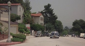 Movie still from “Mulholland Falls” (1996), directed by Lee Tamahori – Cars parked on the side of the road in a residential area; Extreme Wide shot, High angle