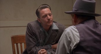 Movie still from “Mulholland Falls” (1996), directed by Lee Tamahori – A man sitting on a bench talking to another man wearing a hat; Close Up shot, Over the shoulder angle