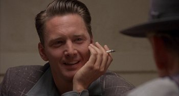 Movie still from “Mulholland Falls” (1996), directed by Lee Tamahori – A young man is smiling while holding a cell phone to his ear; Close Up shot, Over the shoulder angle