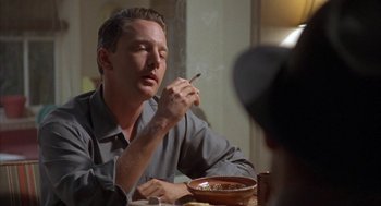Movie still from “Mulholland Falls” (1996), directed by Lee Tamahori – A man sitting at a dinner table smoking a cigarette; Close Up shot, Low angle