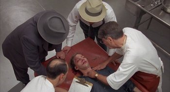 Movie still from “Mulholland Falls” (1996), directed by Lee Tamahori – A group of men standing around a man on the ground; Medium shot, High angle