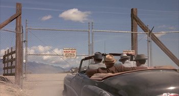 Movie still from “Mulholland Falls” (1996), directed by Lee Tamahori – A group of men riding in the back of an old car; Wide shot, Low angle