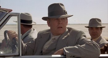 Movie still from “Mulholland Falls” (1996), directed by Lee Tamahori – A man in a suit and hat sitting next to another man in a hat; Close Up shot, Low angle