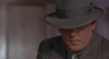 Movie still from “Mulholland Falls” (1996), directed by Lee Tamahori – A person wearing a suit and a hat; Close Up shot, Over the shoulder angle
