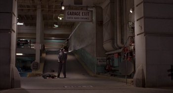 Movie still from “Mulholland Falls” (1996), directed by Lee Tamahori – A man standing next to a fire hydrant in an underground garage; Wide shot, High angle