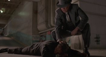 Movie still from “Mulholland Falls” (1996), directed by Lee Tamahori – A man in a suit and a man in a top hat are on the ground; Medium shot, High angle