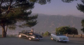 Movie still from “Mulholland Falls” (1996), directed by Lee Tamahori – A man standing next to an old car on a hill; Extreme Wide shot, High angle