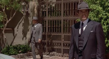 Movie still from “Mulholland Falls” (1996), directed by Lee Tamahori – Two men in suits and hats walking down a sidewalk; Medium shot, Low angle