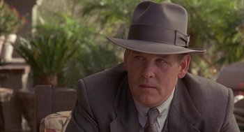 Movie still from “Mulholland Falls” (1996), directed by Lee Tamahori – A person wearing a suit and a hat; Close Up shot, Over the shoulder angle