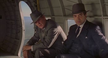 Movie still from “Mulholland Falls” (1996), directed by Lee Tamahori – Two men in suits and hats sitting in a helicopter; Medium shot, Low angle