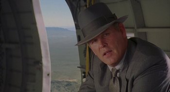 Movie still from “Mulholland Falls” (1996), directed by Lee Tamahori – A man in a suit and a hat looking out the window of an airplane; Close Up shot, Over the shoulder angle