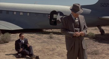 Movie still from “Mulholland Falls” (1996), directed by Lee Tamahori – A man in a suit and hat standing in front of an airplane; Wide shot, Low angle