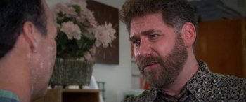 Movie still from “Multiplicity” (1996), directed by Harold Ramis – A person sitting in front of a vase of flowers; Close Up shot, Over the shoulder angle
