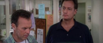 Movie still from “Multiplicity” (1996), directed by Harold Ramis – A man standing next to another man in a room; Close Up shot, Over the shoulder angle