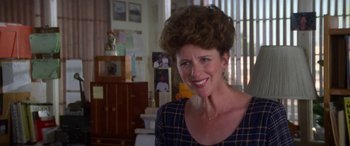 Movie still from “Multiplicity” (1996), directed by Harold Ramis – A woman smiling for the camera in a living room; Close Up shot, Over the shoulder angle