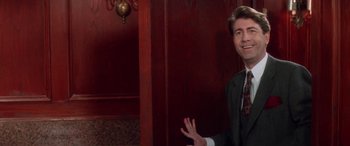 Movie still from “Multiplicity” (1996), directed by Harold Ramis – A man wearing a suit and tie in a room; Medium shot, Over the shoulder angle