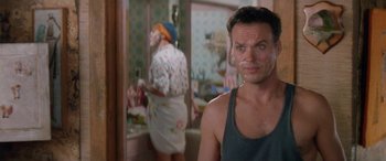 Movie still from “Multiplicity” (1996), directed by Harold Ramis – A man in a green tank top standing in front of a bathroom mirror; Close Up shot, Over the shoulder angle
