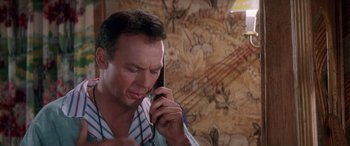 Movie still from “Multiplicity” (1996), directed by Harold Ramis – A man talking on a cell phone in a room; Close Up shot, Over the shoulder angle
