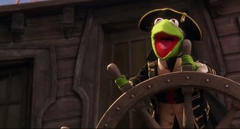 Movie still from “Muppet Treasure Island” (1996), directed by David Lane – A green frog wearing a pirate's hat and holding on to a steering wheel; Medium shot, Low angle