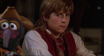 Movie still from “Muppet Treasure Island” (1996), directed by David Lane – A young man with long blonde hair wearing a red vest; Close Up shot, Over the shoulder angle