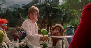 Movie still from “Muppet Treasure Island” (1996), directed by David Lane – A young boy is holding a sword in front of the muppets; Medium shot, Over the shoulder angle