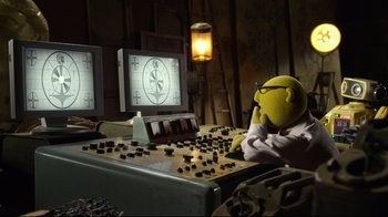 Movie still from “Muppets Most Wanted” (2014), directed by James Bobin – A yellow stuffed animal sitting in front of a computer screen; Medium shot, High angle