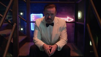 Movie still from “Muppets Most Wanted” (2014), directed by James Bobin – A man in a white suit sitting on a chair; Medium shot, Overhead angle