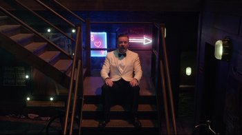 Movie still from “Muppets Most Wanted” (2014), directed by James Bobin – A man in a white suit sitting on some stairs; Wide shot, High angle