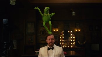 Movie still from “Muppets Most Wanted” (2014), directed by James Bobin – A man in a white suit and a green puppet on top of him; Medium shot, Over the shoulder angle