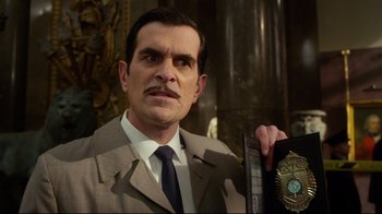 Movie still from “Muppets Most Wanted” (2014), directed by James Bobin – A man in a suit and tie holding a book; Close Up shot, Low angle