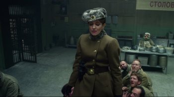 Movie still from “Muppets Most Wanted” (2014), directed by James Bobin – A woman in a military uniform standing in front of a group of people; Medium shot, Over the shoulder angle
