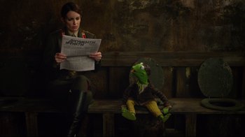 Movie still from “Muppets Most Wanted” (2014), directed by James Bobin – A person sitting on a bench with a stuffed animal; Medium shot, Over the shoulder angle