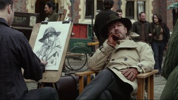 Movie still from “Muppets Most Wanted” (2014), directed by James Bobin – A man sitting in front of an easel with a painting; Medium shot, Over the shoulder angle