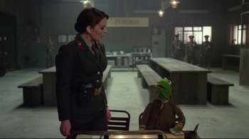 Movie still from “Muppets Most Wanted” (2014), directed by James Bobin – A woman in a military uniform standing next to a man in a suit; Medium shot, Over the shoulder angle