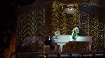 Movie still from “Muppets Most Wanted” (2014), directed by James Bobin – A man sitting at a piano in front of a stage; Extreme Wide shot, High angle