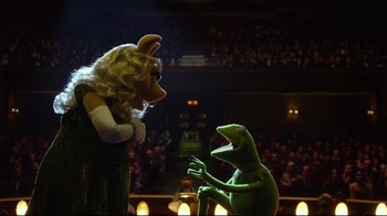 Movie still from “Muppets Most Wanted” (2014), directed by James Bobin – A woman and a man are standing in front of an audience; Medium shot, Over the shoulder angle