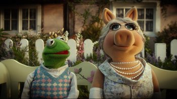 Movie still from “Muppets Most Wanted” (2014), directed by James Bobin – A couple of muppets standing next to each other in a garden; Close Up shot, Over the shoulder angle