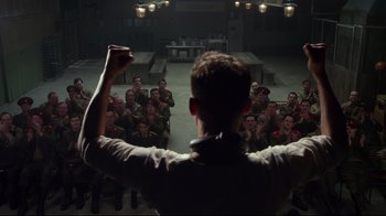 Movie still from “Muppets Most Wanted” (2014), directed by James Bobin – A group of people in a room watching a man with his hands raised; Medium shot, Low angle