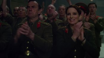 Movie still from “Muppets Most Wanted” (2014), directed by James Bobin – A group of people in uniform clapping in front of a crowd; Medium shot, Over the shoulder angle