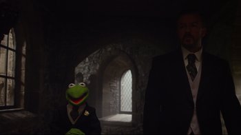 Movie still from “Muppets Most Wanted” (2014), directed by James Bobin – A man in a suit standing next to a puppet; Medium shot, Low angle