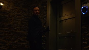 Movie still from “Muppets Most Wanted” (2014), directed by James Bobin – A man standing next to a door in a dark room; Medium shot, Low angle