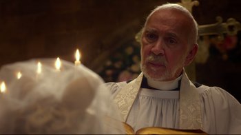 Movie still from “Muppets Most Wanted” (2014), directed by James Bobin – An older man wearing a priest's robe and holding a bible; Close Up shot, Low angle