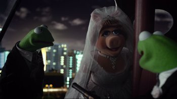 Movie still from “Muppets Most Wanted” (2014), directed by James Bobin – A bride and a frog are in front of a city skyline at night; Close Up shot, Over the shoulder angle